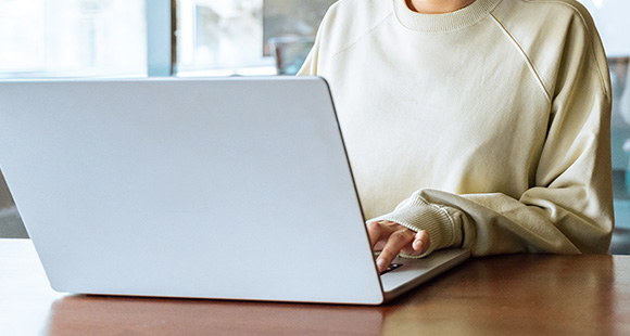 person using laptop in a casual setting with soft sweater focused on digital work and productivity